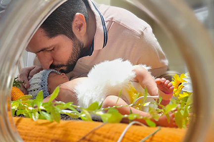 Dad kissing baby in NICU