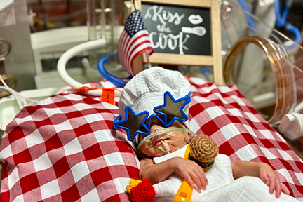 NICU baby dressed as a chef for July 4th