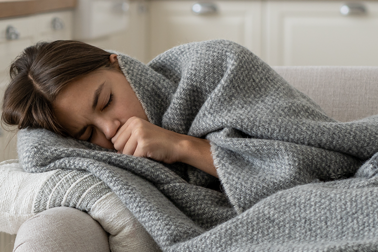 sick woman on couch under blanket