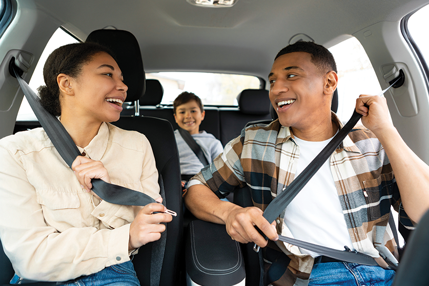 family of three buckling seat belts in car